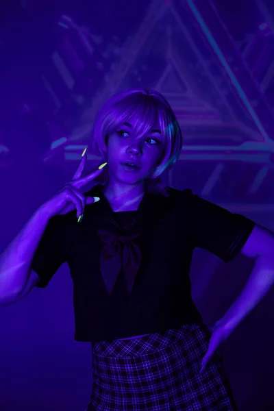 Blonde Frau in Schuluniform mit Hand an der Hüfte und Siegeszeichen in blauem Neonlicht im Anime-Stil — Stockfoto