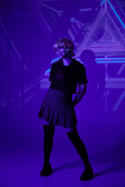 Full length of woman in school uniform in blue neon light on abstract backdrop, anime concept — Stock Photo