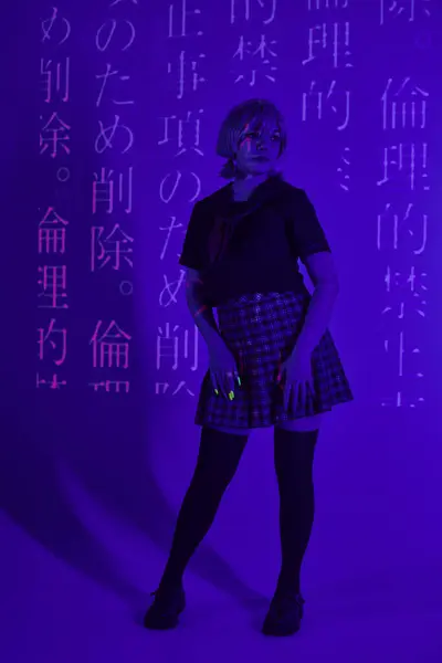 Молода жінка в шкільній формі в блакитному неоновому світлі з проекцією ієрогліфів, концепція косплей — стокове фото
