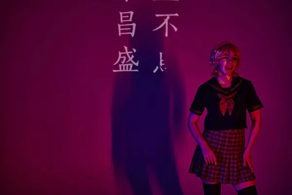 Anime woman in school uniform sticking out tongue in neon light on purple backdrop with hieroglyphs — Stock Photo