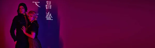 Студенты косплея в форме в неоновом свете на фиолетовом фоне с иероглифами проекции, баннер — стоковое фото