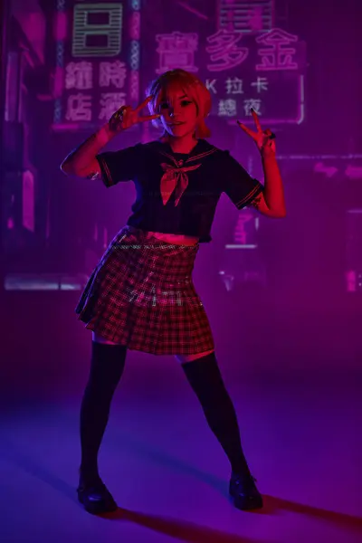 Cosplay-Frau in Schuluniform zeigt Siegeszeichen auf lila Neonkulisse mit Hieroglyphen — Stockfoto