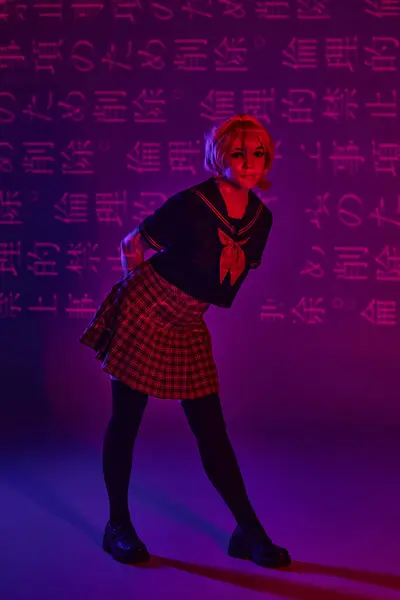 Hübsche Frau in Schuluniform posiert auf neonlila Hintergrund mit Hieroglyphen, Anime-Trend — Stockfoto