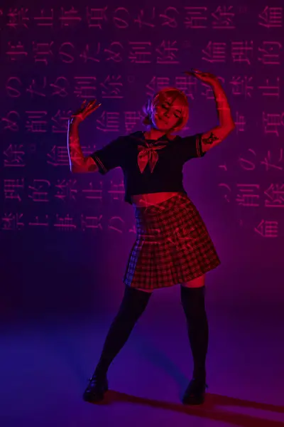 Femme anime tatouée en uniforme scolaire posant sur fond violet néon avec projection de hiéroglyphes — Photo de stock