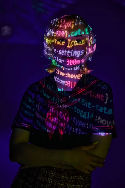 Donna in uniforme studenti in neon simboli di programmazione proiezione su sfondo blu, concetto di cosplay — Foto stock