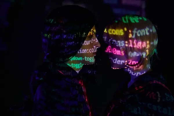 Side view of young couple with neon programming lettering on dark backdrop, anime style concept — Stock Photo