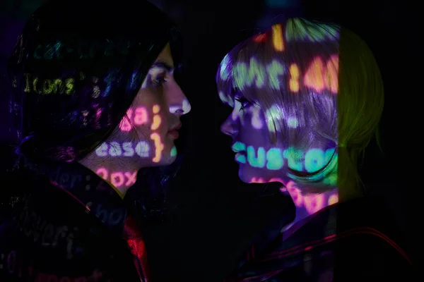 Vista laterale di giovani studenti con lettere di programmazione al neon su sfondo scuro, concetto di tendenza anime — Foto stock