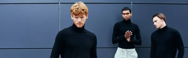 Appealing young men in black turtlenecks with accessories posing by wall outside, fashion, banner — Stock Photo