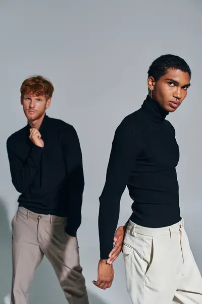 Vertical shot of two multicultural men in black elegant turtlenecks looking at camera, fashion — Stock Photo