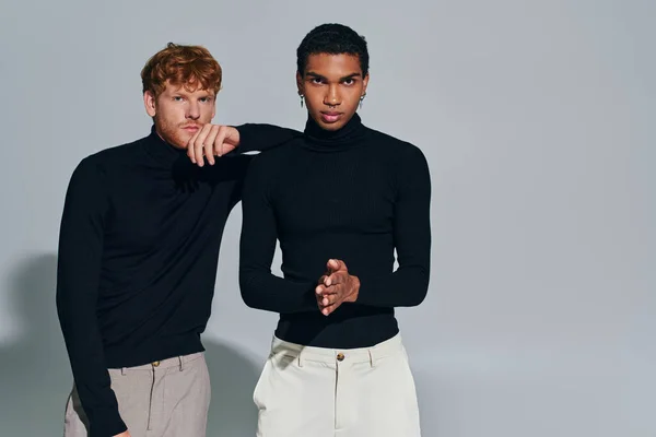 Deux beaux hommes multiraciaux regardant la caméra sur fond gris, coude sur épaule, mode — Photo de stock