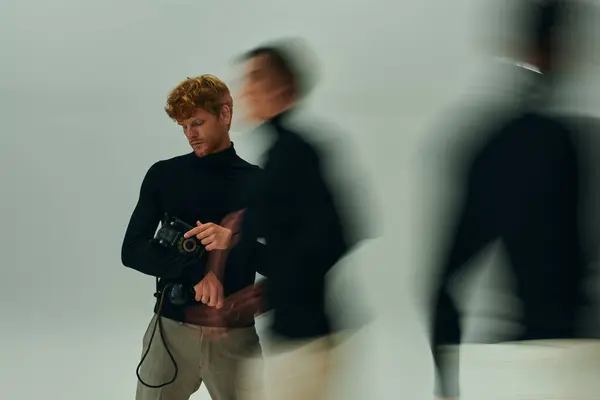 Hombre barbudo de pelo rojo con teléfono retro en las manos posando con otros hombres en movimiento, concepto de moda - foto de stock