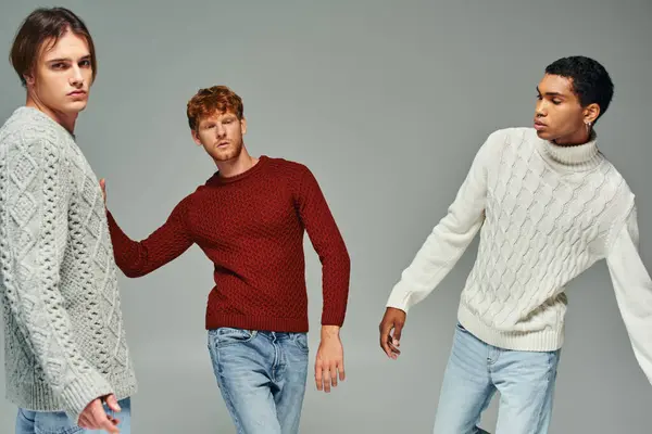 Trois beaux modèles masculins multiethniques en pulls confortables décontractés posant en mouvement, le pouvoir des hommes — Photo de stock