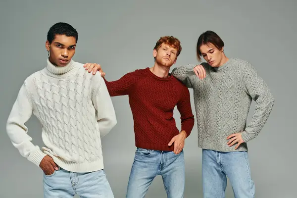 Modelos masculinos inter-raciais elegantes em suéteres casuais vibrantes posando em pano de fundo cinza, poder dos homens — Fotografia de Stock