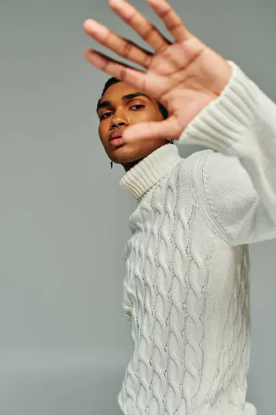 Hombre afroamericano guapo en suéter blanco con palma en frente de su cara, concepto de moda - foto de stock