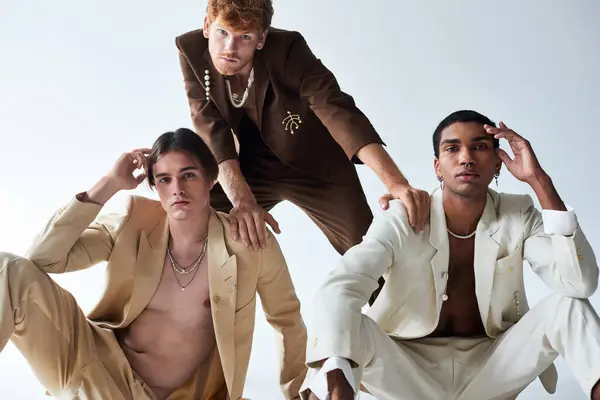 Boa aparência diversos cavalheiros em elegante terno elegante posando no chão com fundo cinza, moda — Fotografia de Stock