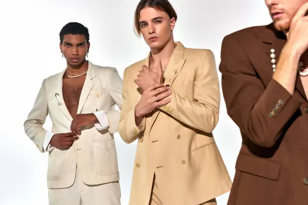 Cropped view of man in beige suit posing with other two male models in suits on backdrop, fashion — Stock Photo