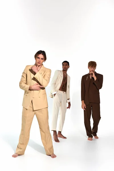 Bellissimi uomini diversi in eleganti abiti luminosi in posa sulla macchina fotografica su sfondo bianco, concetto di moda — Foto stock