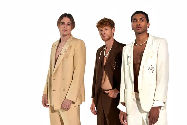 Gut aussehendes junges Trio in eleganten Anzügen mit Accessoires stehend und in die Kamera blickend, Männerpower — Stockfoto