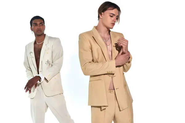 Appealing sexy male models in unbuttoned suits posing on white backdrop looking away, fashion — Stock Photo