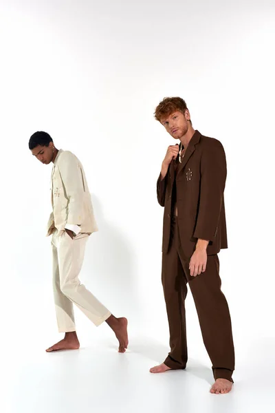 Вертикальний знімок хорошого вигляду різноманітних чоловічих моделей в костюмах позує босоніж на білому тлі — стокове фото
