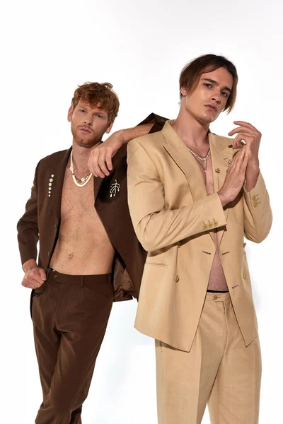 Plan vertical de séduisants hommes élégants en costumes élégants regardant caméra, coude sur épaule, mode — Photo de stock