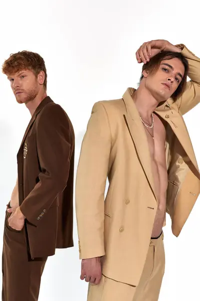 Vertical shot of young handsome men standing back to back and looking at camera, fashion concept — Stock Photo