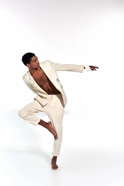 Homem afro-americano bonito em terno elegante posando em movimento e olhando para longe, conceito de moda — Fotografia de Stock