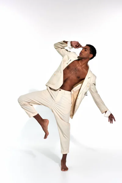 African american good looking sexy man in suit posing in motion with raised leg and arms, fashion — Stock Photo