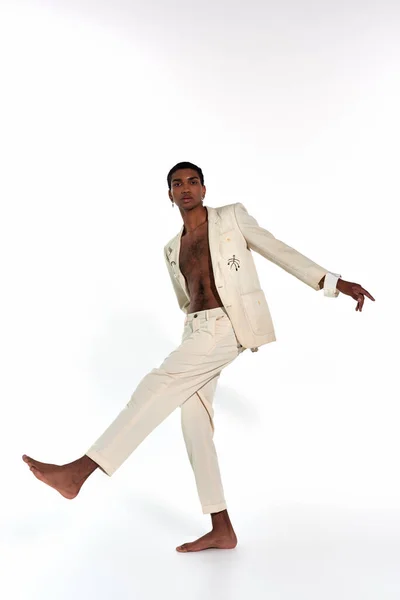 Tiro vertical de atraente homem afro-americano em terno posando em movimento olhando para a câmera, moda — Fotografia de Stock