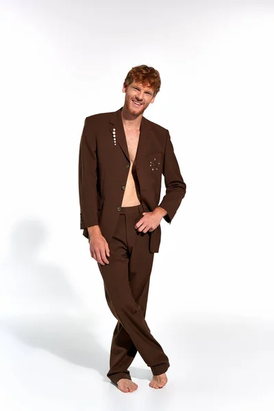 Vertical shot of handsome cheerful man in elegant suit with hand on belt smiling at camera, fashion — Stock Photo