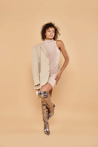Full length of charming african american woman posing in autumn blazer and mini dress on beige — Stock Photo