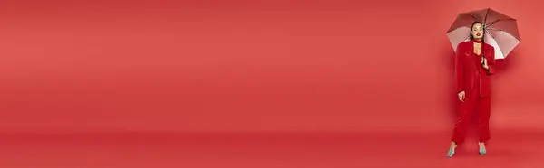 Банер, брюнетка афро-американська модель в червоному блістері і штани, що стоять під парасолькою — стокове фото