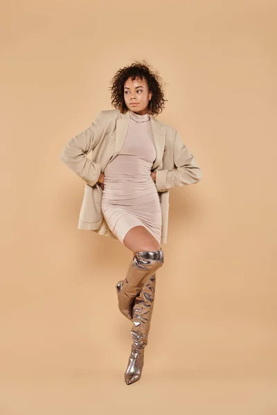 Volle Länge der afrikanisch-amerikanischen Frau mit lockigem Haar posiert im herbstlichen Blazer und Kleid auf beige — Stockfoto