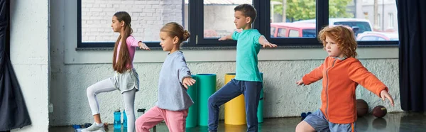 Niños y niñas preadolescentes lindo ejercicio con manos asidas, rodillas levantadas, deporte infantil, bandera - foto de stock