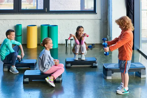 Crianças felizes pré-adolescentes em steppers fitness com halteres sorrindo alegremente, esporte infantil — Fotografia de Stock