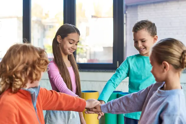 Fröhliche Jungen und Mädchen in Sportkleidung, die sich die Hände aufeinanderlegen und glücklich lächeln, Kindersport — Stockfoto