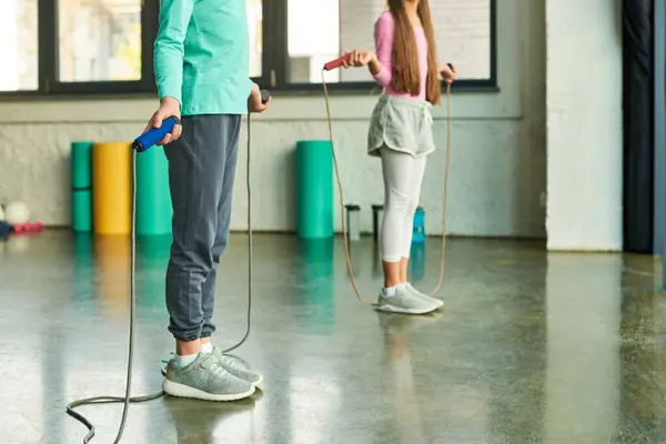 Recortado vista de niño y niña en ropa deportiva con saltar las cuerdas en las manos, deporte infantil - foto de stock