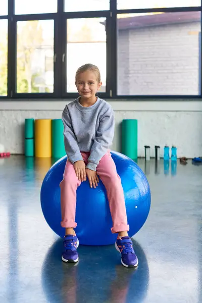 Cute preadolescent girl in sportswear sitting on fitness ball and looking at camera, child sport — Stock Photo