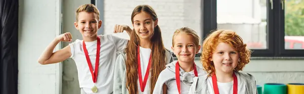 Happy children in sportswear with golden medals smiling joyfully at camera, child sport, banner — Stock Photo
