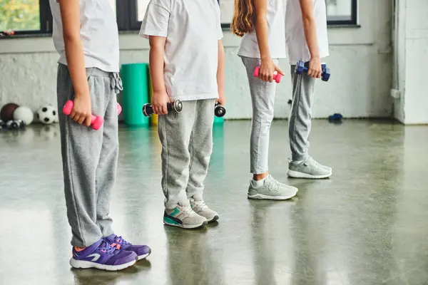 Cropped view of preadolescent children in sportswear exercising with dumbbells, child sport — Stock Photo
