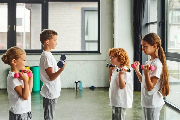 Pretty little children standing opposite each other and exercising with dumbbells, child sport — Stock Photo