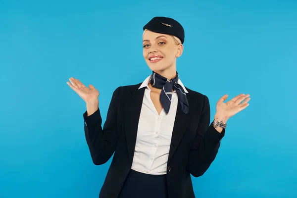 Welcoming stewardess with open arms posing in elegant uniform on blue, professional hospitality — Stock Photo