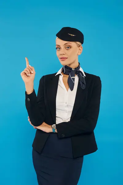 Elegante Stewardess in Corporate Uniform zeigt Richtung mit dem Finger auf Blau, Reisebranche — Stockfoto