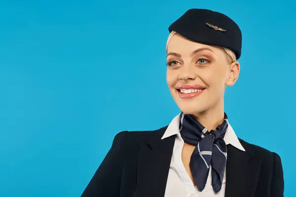 Ritratto di giovane donna allegra in elegante uniforme di hostess aerea distogliendo lo sguardo sullo sfondo blu — Foto stock
