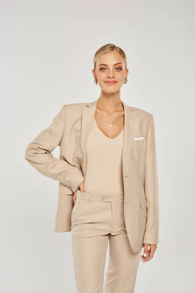 Giovane modella donna in abbigliamento casual beige in posa con mano sul fianco su grigio, fashion shoot — Foto stock