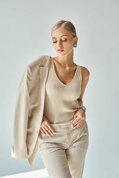 Jeune femme sensuelle dans des vêtements élégants beige posant sur fond gris, mode moderne shoot — Photo de stock