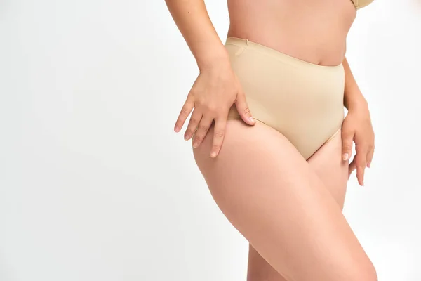 Cropped view of young plus size woman in beige panties with hands near curvy hips on white, beauty — Stock Photo