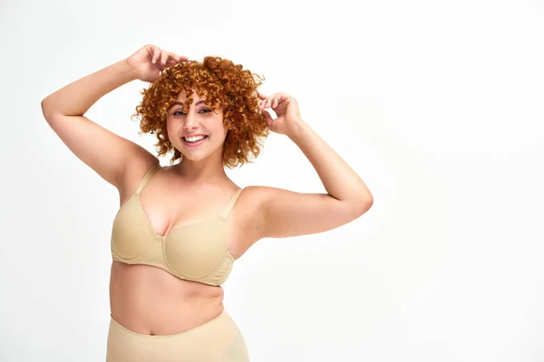 Carefree redhead woman with beautiful curvy body posing in beige lingerie on white, self-confidence — Stock Photo