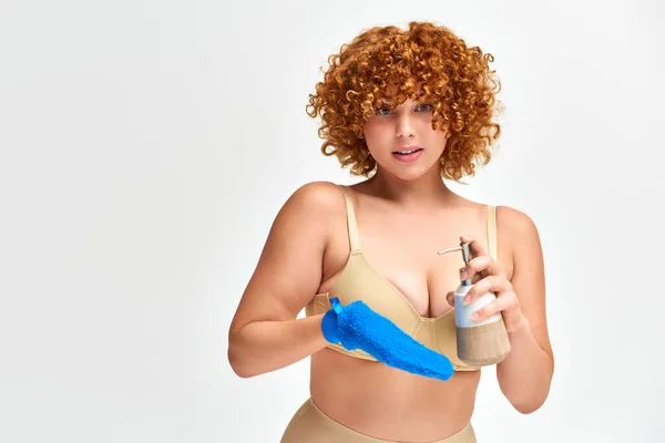 Ruiva plus size mulher em lingerie bege com luva de banho e dispensador de sabão líquido no branco — Fotografia de Stock