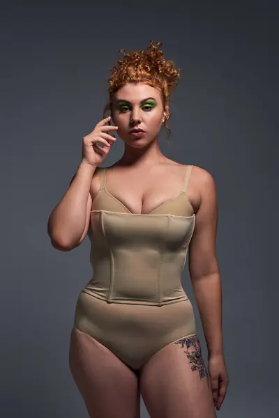 Body positivity, young redhead woman with curvy body in beige lingerie on dark grey backdrop — Stock Photo